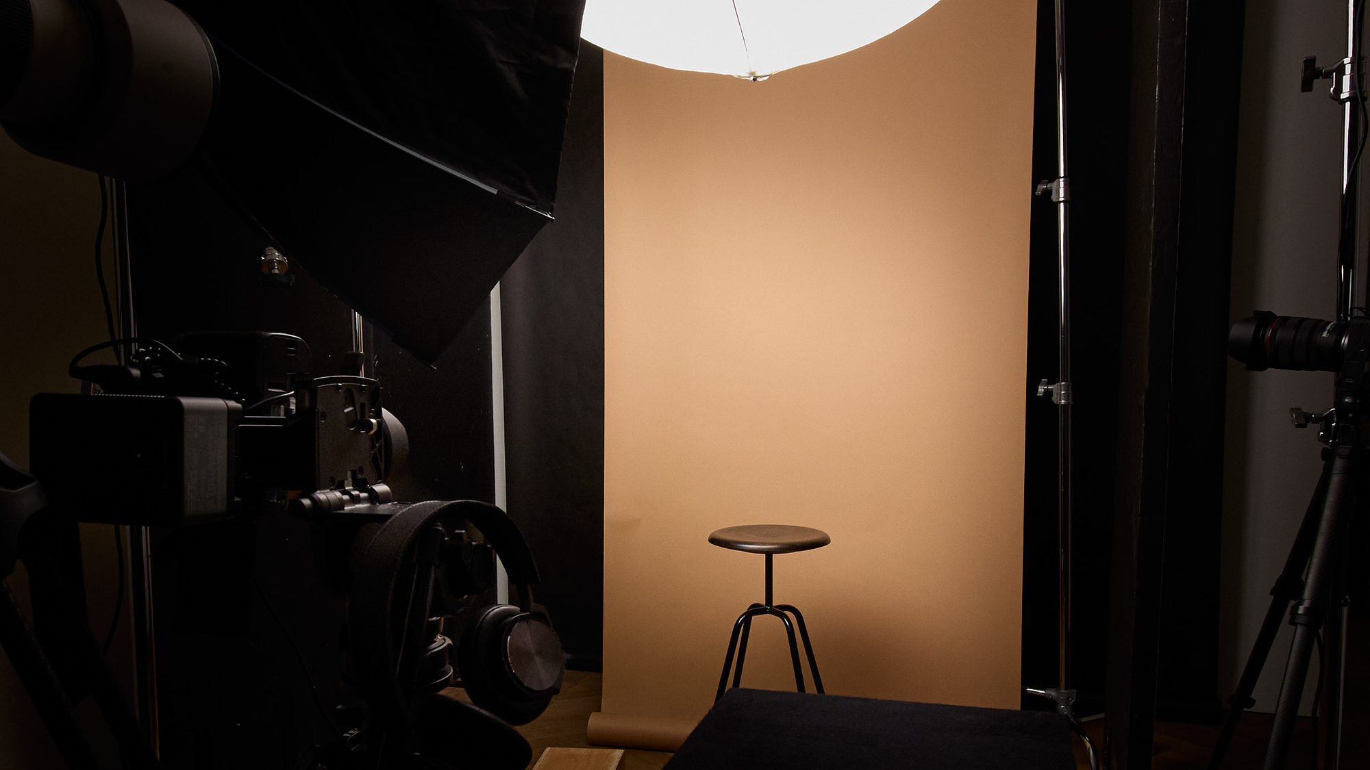 Das Aufnahme-Studio in München: ein Hocker im Lichtkegel vor warmem Hintergrund, daneben Kamera und Setup